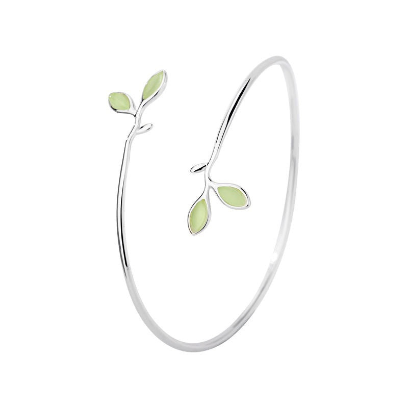 Close up of silver open cuff bracelet with green leaf details on wrist