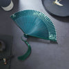 Open green folding fan with white floral patterns and a matching tassel
