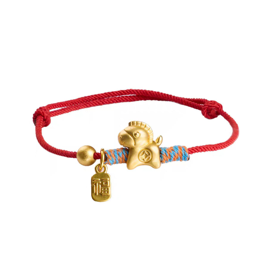 Close up of a red handwoven bracelet with a gold horse charm and Fu pendant on a white background