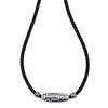 Close-up of a silver nine-eye dzi bead pendant on a black cord