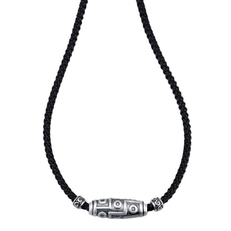 Close-up of a silver nine-eye dzi bead pendant on a black cord