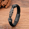Black leather bracelet with a patterned Dzi bead and dark metal clasp on a wooden surface