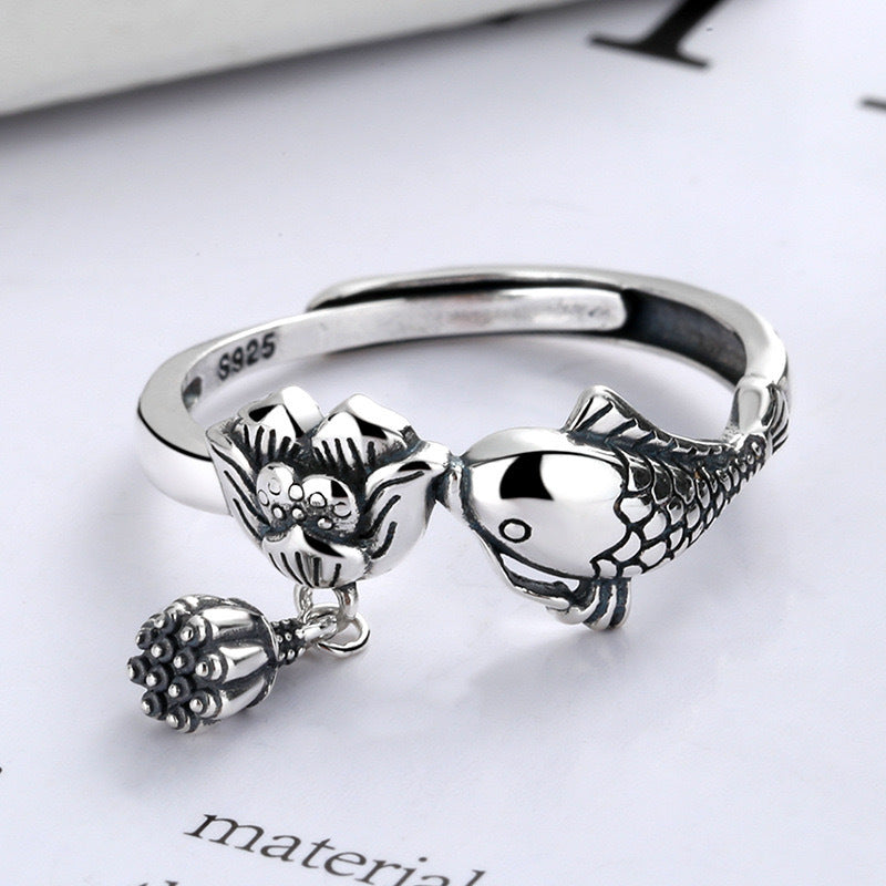 Close up of a silver ring with a koi fish and lotus flower design