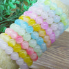 Stack of pastel colored translucent glass bead bracelets on a wooden surface