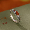 Close up of a silver ring with a red gourd stone and cloud carvings