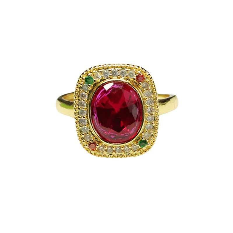 Gold tone ring with a large red lab-created ruby and geometric halo setting