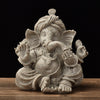 Front view of a seated Ganesha resin statue with a sandstone texture on a wooden surface.