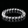 A close-up view of a clear crystal beaded bracelet on a black reflective surface