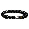 Close up of a black sheen obsidian bracelet with gold tiger eye beads on a stone surface