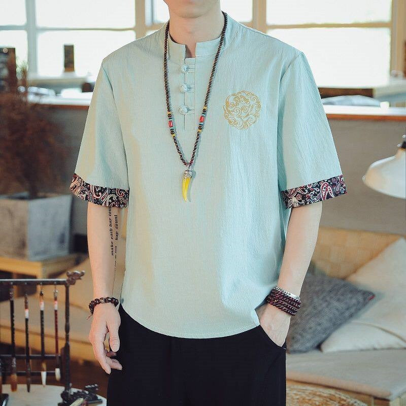 Man wearing a light blue short sleeve shirt with dragon embroidery on the chest