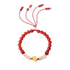 Red beaded bracelet with a gold flower charm and adjustable cord ties on a white background