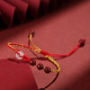 Close up of a red and yellow braided cord bracelet with beads on a red background