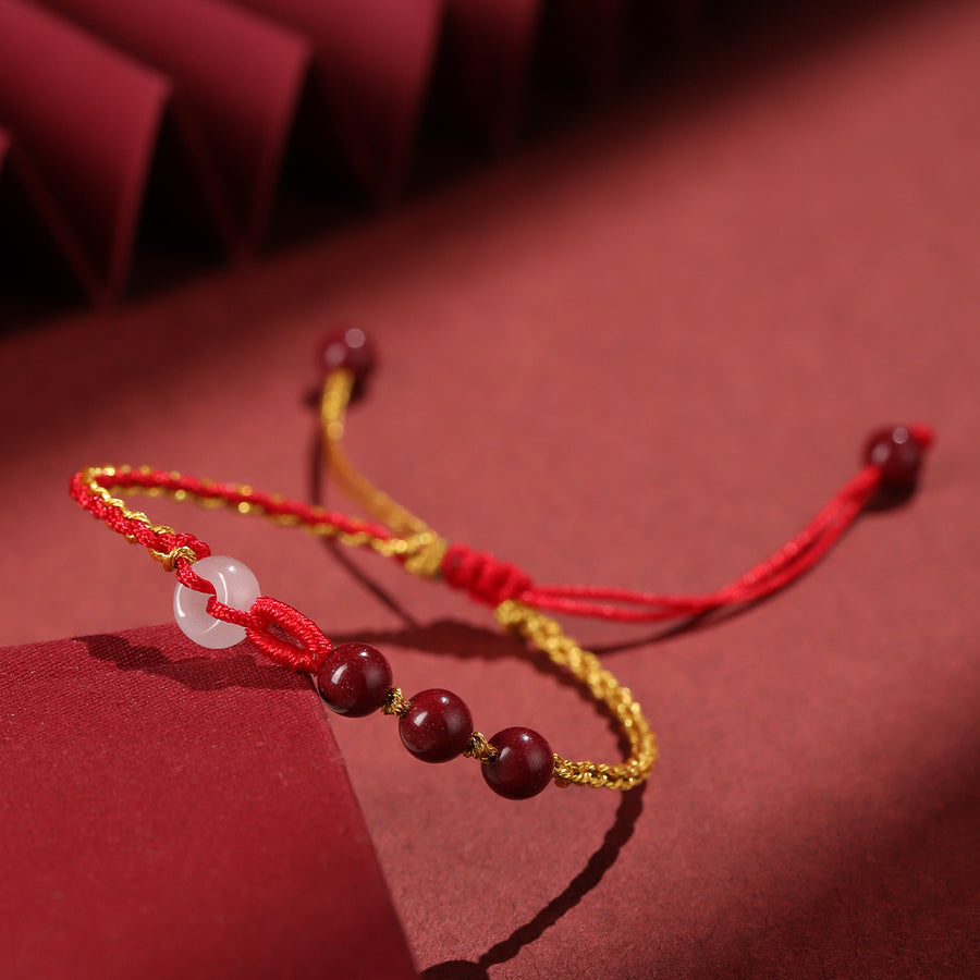 Close up of a red and yellow braided cord bracelet with beads on a red background