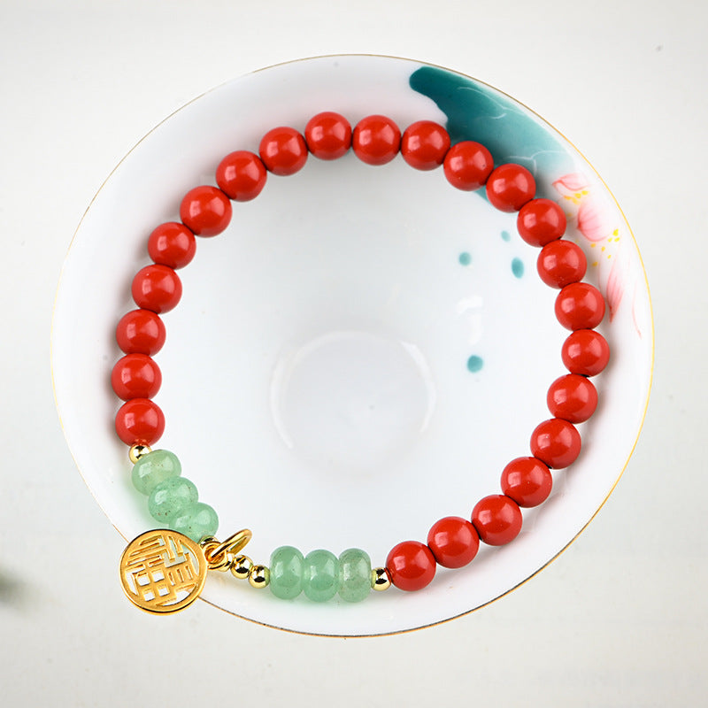 Red cinnabar bead bracelet with a gold-tone circular charm resting on a white dish