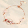 Close up of a rose gold tone silver bracelet with a white jade donut, red koi fish and pink beads