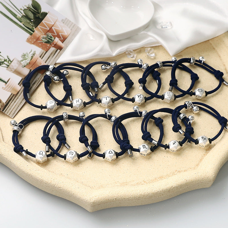 A collection of dark blue woven bracelets with silver cube charms showing zodiac symbols