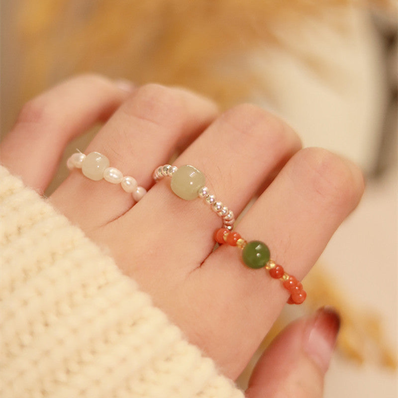 Close up of a hand wearing a beaded elastic ring with small pearls and stones