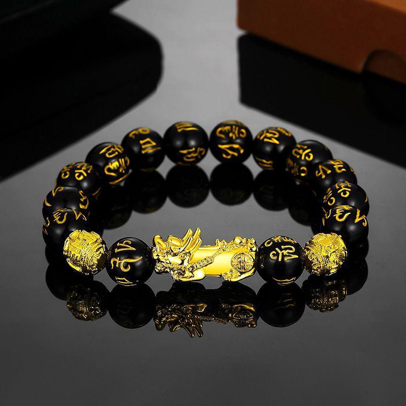 Gold-tone double Pixiu bracelet with black round beads on a reflective surface