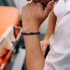 Man wearing a stretch bracelet with square blue stones and brown tiger eye beads