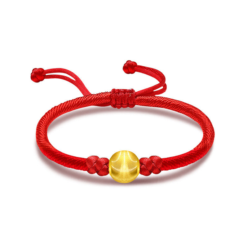 Close up of a red braided cord bracelet with a polished round gold bead in the center