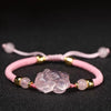 Close-up of a pink crystal Pixiu charm on a braided pink cord bracelet