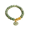 Green jade beaded bracelet with a hanging peace buckle charm on a yellow background