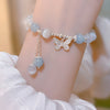 A beaded bracelet with a silver butterfly charm worn on a wrist.