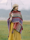 Woman wearing a colorful knitted Tibetan shawl outdoors holding an umbrella