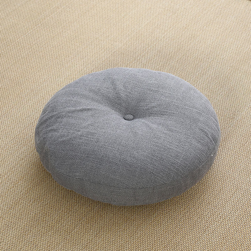 Round grey linen meditation cushion on a woven mat