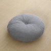 Round grey linen meditation cushion on a woven mat
