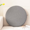 Gray round memory foam seat cushion resting on a beige sofa