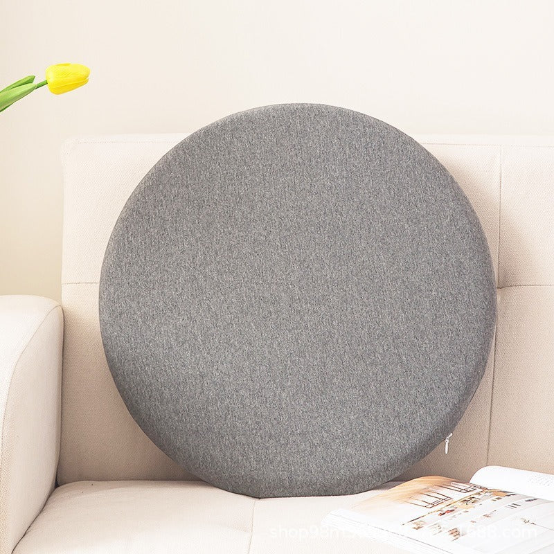 Gray round memory foam seat cushion resting on a beige sofa