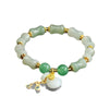 Close up of a light green jade bracelet with bamboo shaped beads and a gold tone money bag charm