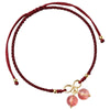 Close up of a wrist wearing a red woven bracelet with pink crystal beads and a gold knot