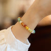 A wrist wearing a colorful multi-gemstone disc bead bracelet with gold-tone spacers