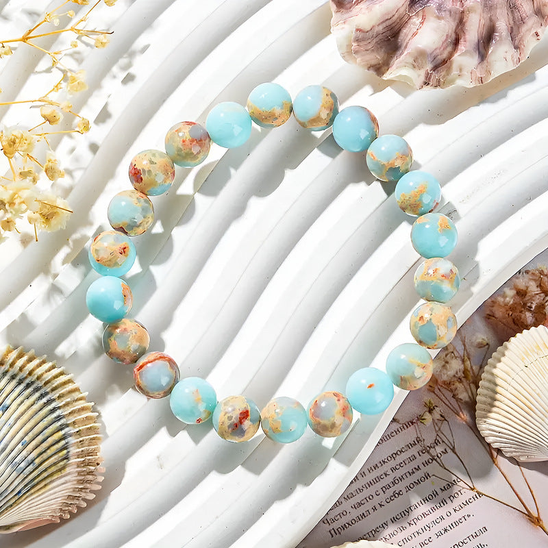 Close up view of a natural stone beaded bracelet with blue patterned beads on a white surface