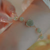 Gold-tone chain bracelet with green imitation jade rose flower on wrist