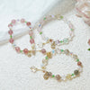 Three beaded bracelets with floral patterns and a tulip charm on a white textured surface.