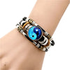 Close up of a black leather wrap bracelet with a blue Yin Yang glass charm on a wrist