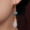 A pair of drop earrings featuring a white jade stone and gold-tone metal design
