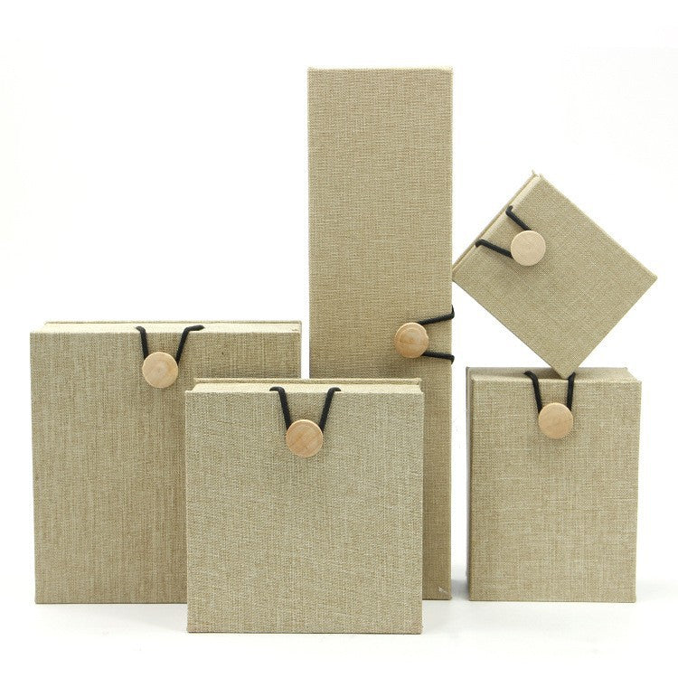 Stack of beige linen-textured jewelry boxes with wood button closures
