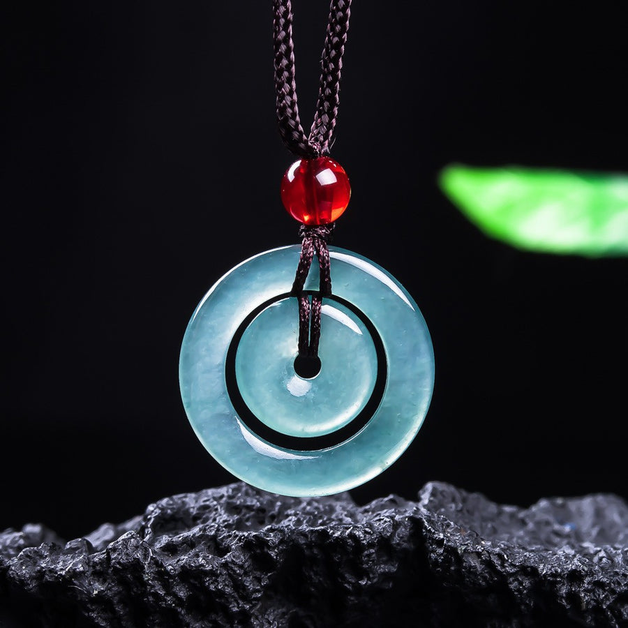 Close-up of a translucent blue green jade double ring pendant on a dark cord