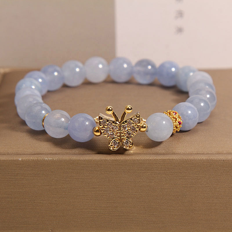 Light blue crystal bead bracelet with a gold-tone butterfly charm on a box