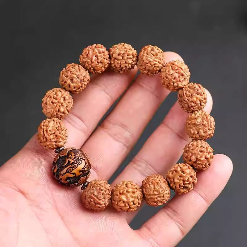A hand holding a brown bodhi seed bracelet with a dark carved Pixiu bead.