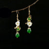 Pair of vintage floral drop earrings with white shell flower and green bead on a branch