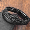 Close-up of a black woven leather and steel chain bracelet on a wooden surface