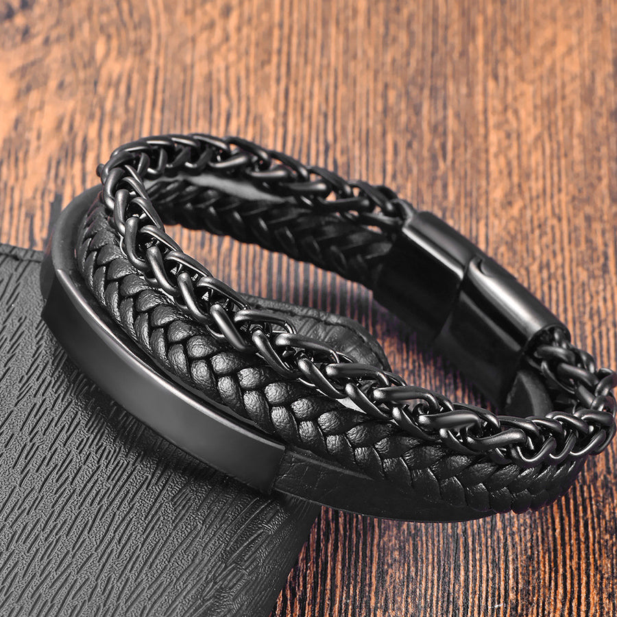 Close-up of a black woven leather and steel chain bracelet on a wooden surface