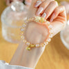 Close up of pink incense ash glass bead bracelet with white fox and gold lotus charm on wrist