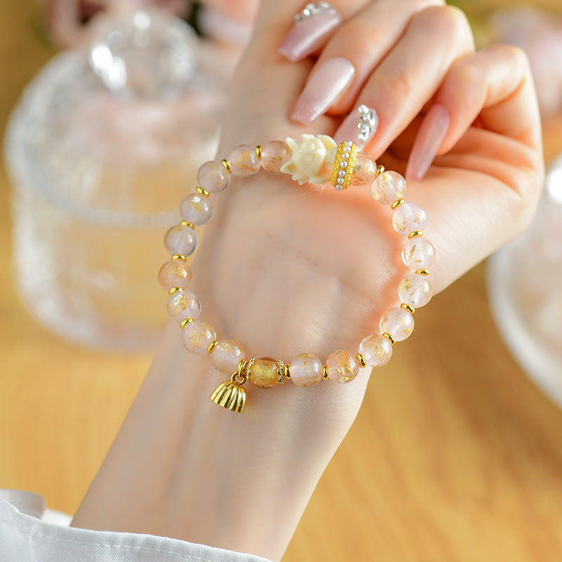Close up of pink incense ash glass bead bracelet with white fox and gold lotus charm on wrist