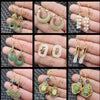 Hand holding various styles of green and white jade earrings with gold hooks